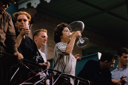 A young woman on a balcony, drinking from an outsize champagne coupe during Mardi Gras in New Orleans, Louisiana, 1961