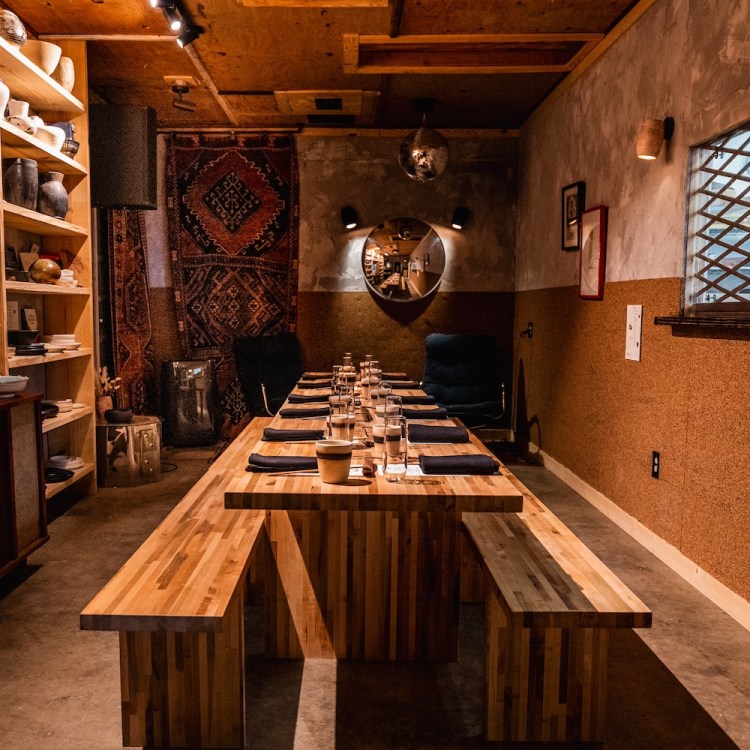 a long wooden table set for dinner inside a warm ceramics studio