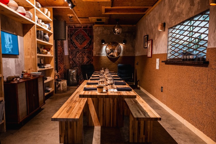 a long wooden table set for dinner inside a warm ceramics studio