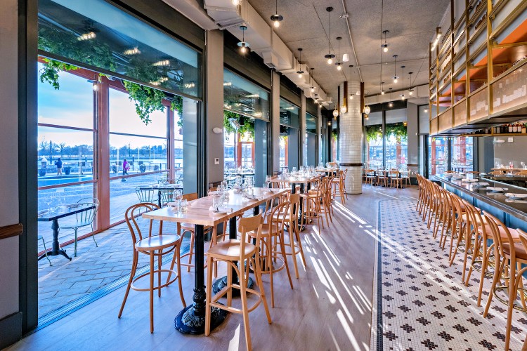 a light filled wine bar with a black and white tiled floor and wall of windows