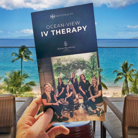 A Next Health brochure for "Ocean-View IV Therapy" held in a hand at the Four Seasons Maui at Wailea