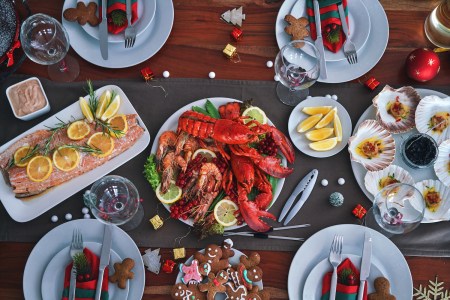 Family Having Christmas Dinner with Salmon Fish Fillet, Scallops, Lobster, Shrimps and gingerbread men