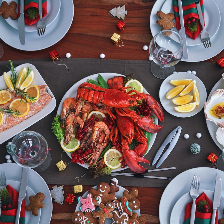 Family Having Christmas Dinner with Salmon Fish Fillet, Scallops, Lobster, Shrimps and gingerbread men