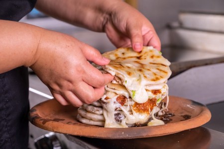 a woman stacking Typical Salvadorian pupusas