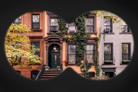 A binocular view looking into the windows of brownstones in Manhattan. Why are we all so obsessed with seeing in other people's homes these days?