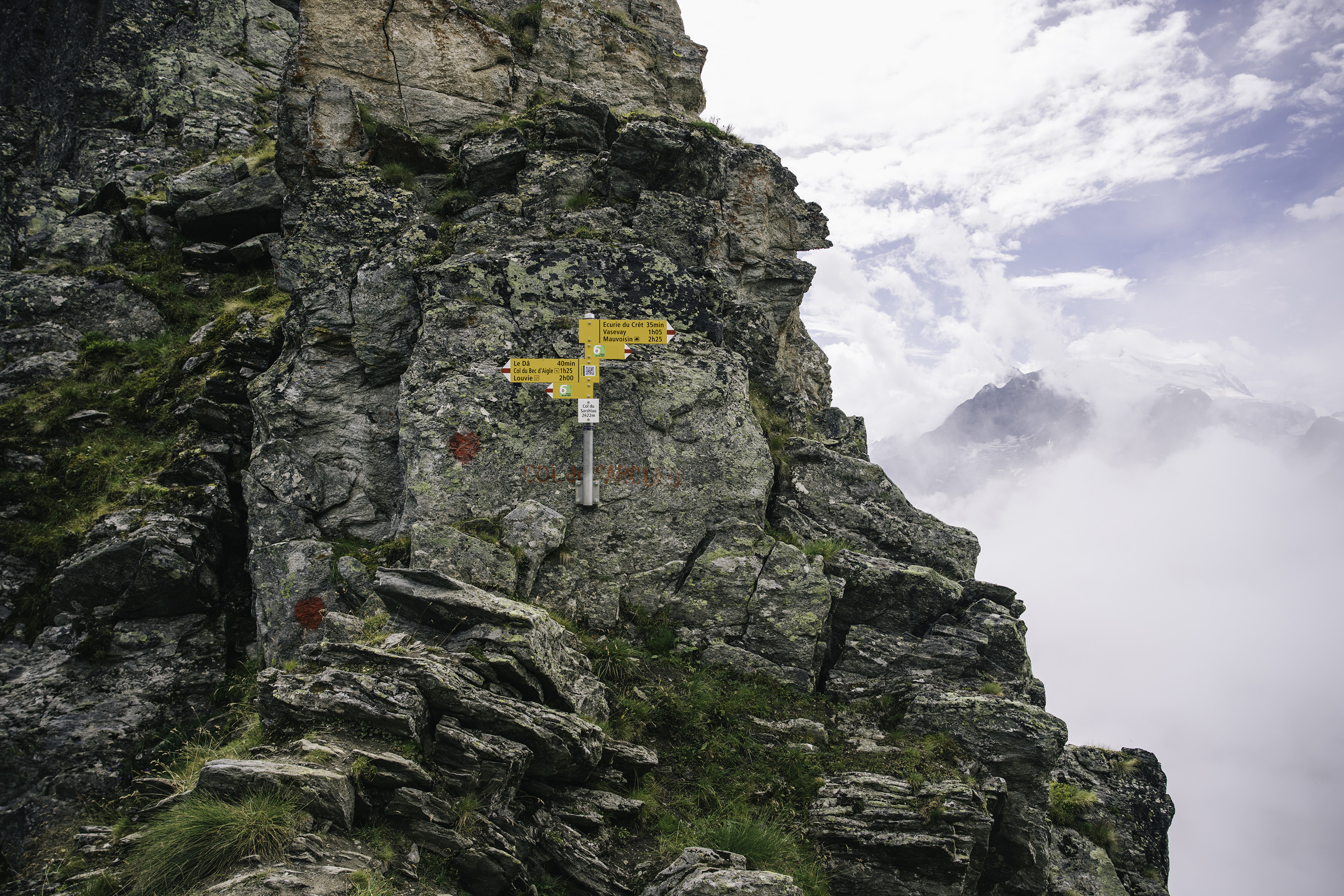 A view of Swiss trail signs, with only clouds and sky to the right.