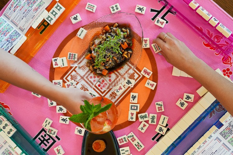 Mahjong tiles spread out on a pink and orange table