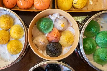 a bunch of wooden steamer baskets filled with colorful dumplings