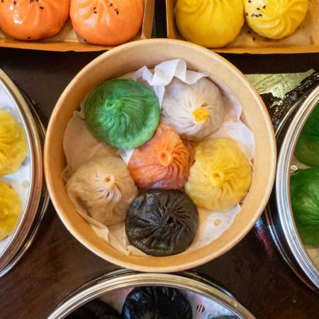 a bunch of wooden steamer baskets filled with colorful dumplings