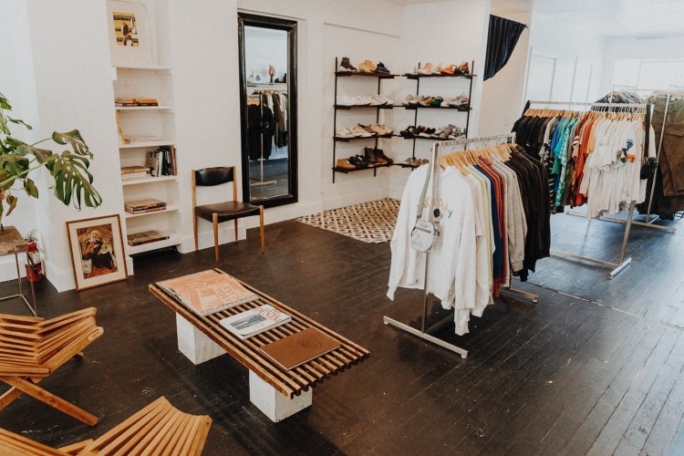 Clothing racks and shelves of shoes and a mirror inside of ReLove