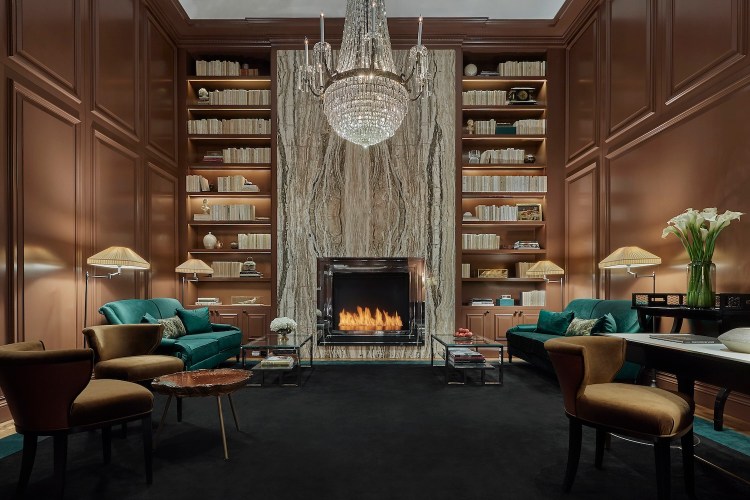 library with chandelier, fireplace, teal chairs