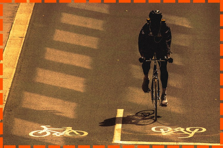 A cyclist in a bike lane, tinted in sepia, with orange jotted lines around the border.