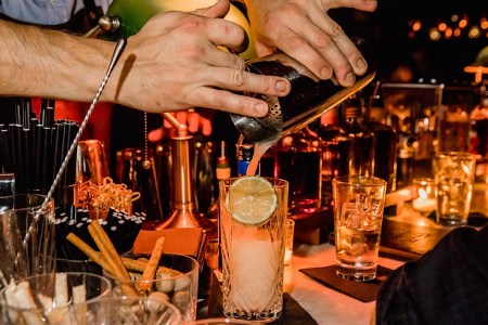 Close-up of hands pouring a cocktail into a glass