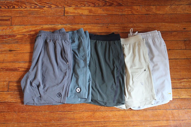 A variety of Vuori shorts spread across a wooden floor. We reviewed five different Vuori shorts for men.